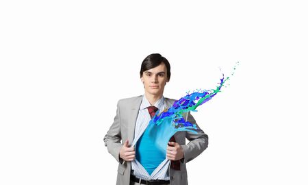 Young businessman acting like super hero and tearing his shirt offの写真素材