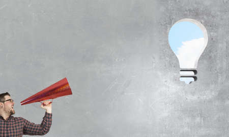 Hipster man screaming emotionally in red paper trumpet