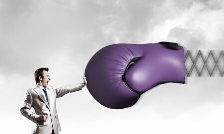 Young determined businessman fighting boxing glove on springの写真素材