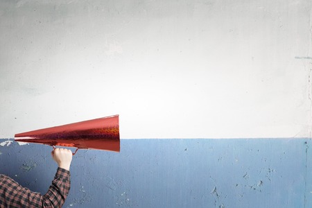 Hand of man holding red paper trumpetの写真素材
