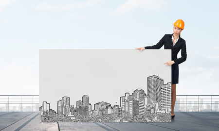 Attractive woman engineer pointing with finger at white blank bannerの写真素材