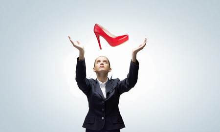 Beautiful young woman in suit under rain of falling shoesの写真素材