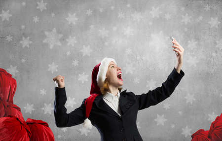 Young businesswoman in Santa hat screaming in mobile phoneの写真素材