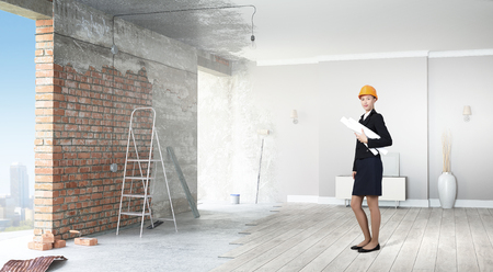 Happy smiling young engineer woman in hardhat holding project paperの写真素材