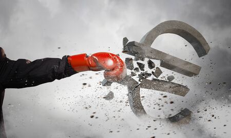 Hand of businessman in boxing gloves breaking euro signの写真素材