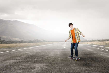 Teenager guy riding skateboard on asphalt roadの写真素材