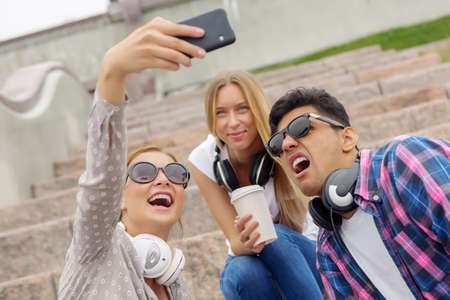 Group of young people outdoors laughing and doing selfieの写真素材