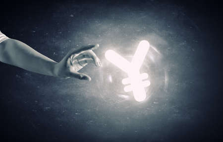 Close up of human hand holding yen symbol on gray backgroundの写真素材