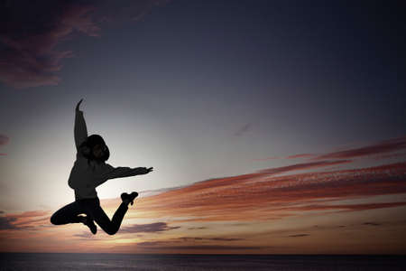 Silhouette of young girl in jump presenting freedom and happiness conceptの写真素材
