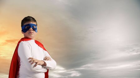 Boy wearing cape and mask pretending to be superheroの写真素材