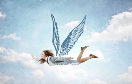 Young businesswoman in suit flying high in skyの写真素材