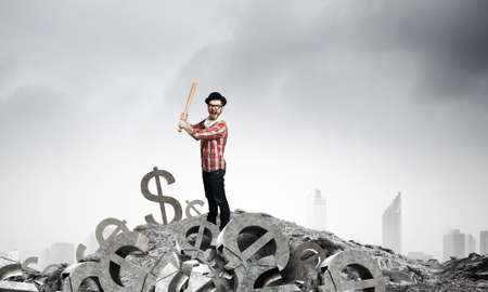 Young man with baseball bat in anger breaking currency sign