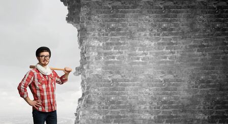 Young man with baseball bat in anger breaking wallの写真素材
