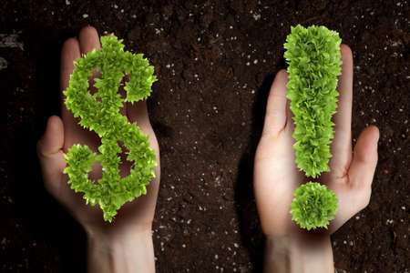 Hands holding green dollar sign and soil at backgroundの写真素材