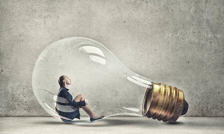 Young woman sitting inside of glass light bulb