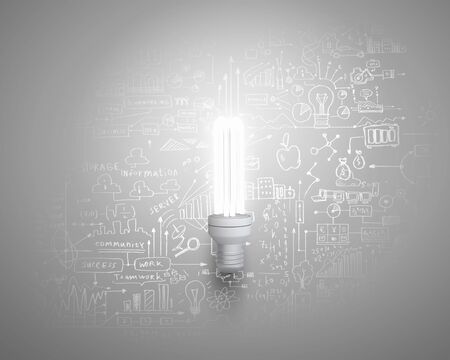 Glass glowing light bulb and business sketched ideas on wallの写真素材