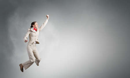 Confident businesswoman ready for fight over gray backgroundの写真素材