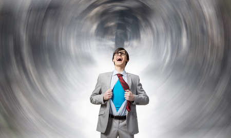 Young businessman acting like super hero and tearing his shirt offの写真素材