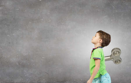 School aged cute active boy with key on backの写真素材