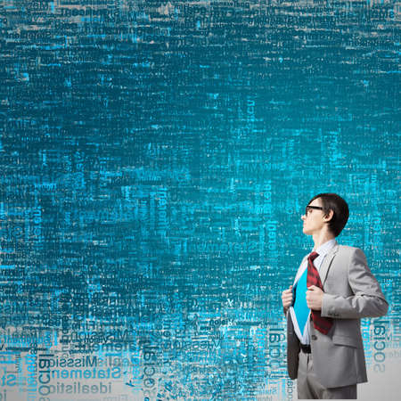 Young businessman acting like super hero and tearing his shirt offの写真素材