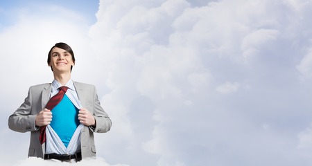 Young businessman acting like super hero and tearing his shirt offの写真素材