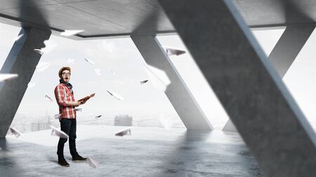 Hipster guy with book in hands in modern interiorの写真素材