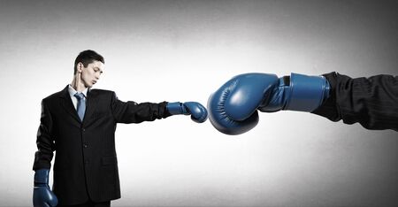 Handsome determined businessman wearing boxing gloves over gray backgroundの写真素材
