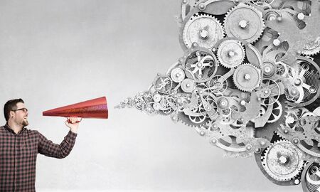 Hipster man screaming emotionally in red paper trumpetの写真素材