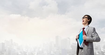 Young businessman acting like super hero and tearing his shirt offの写真素材