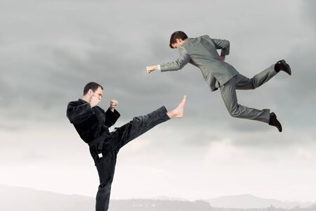Young determined karate man fighting with businessman in suit