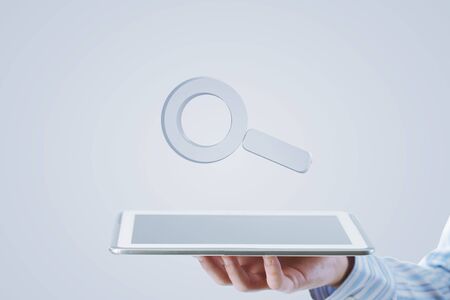 Businessman hand holding search glass icons in palmの写真素材