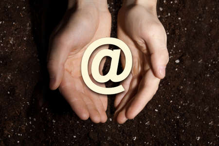 Close up of male hands showing email sign on soil backgroundの写真素材