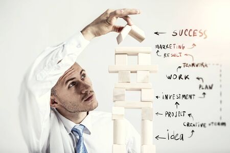 Young businessman making pyramid with empty wooden cubesの写真素材