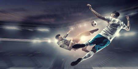 Young businessman in suit playing football at stadiumの写真素材