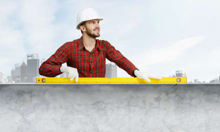 Builder man in checked shirt using measuring levelの写真素材