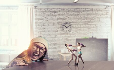 Attractive student girl in red glasses peeping from under tableの写真素材