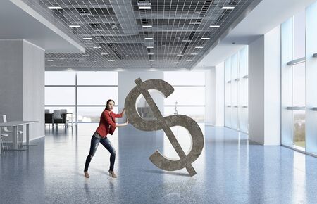 Young woman in modern interior pushing dollar symbolの写真素材