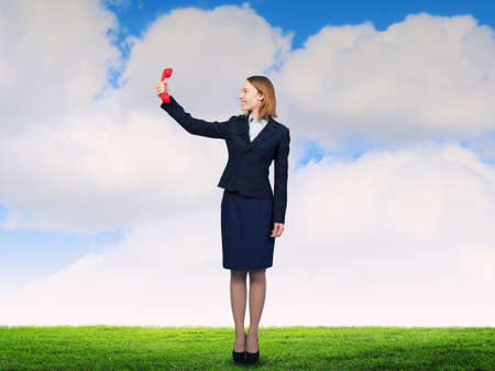 Young businesswoman with red phone receiver in handsの写真素材