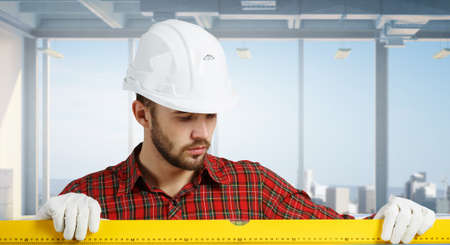 Builder man in checked shirt using measuring level