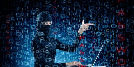Hacker woman in dark clothes using laptop against digital background