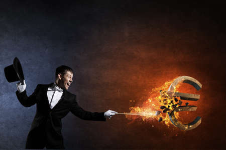 Young cheerful businessman making tricks with magic hatの写真素材