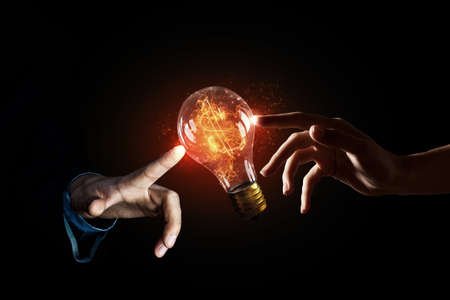 Close up of human hands touching with finger light bulbの写真素材