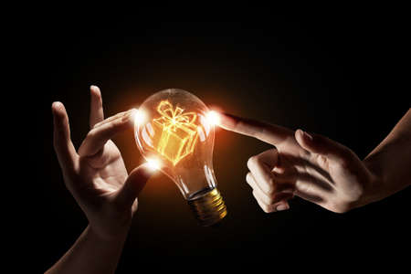 Close up of human hands touching with finger light bulbの写真素材