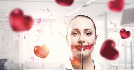 Attractive woman applying red lipstick with brushの写真素材