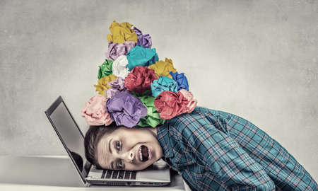 Woman programmer pressed with paper balls to laptopの写真素材