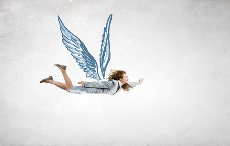 Young businesswoman in suit flying high in skyの写真素材