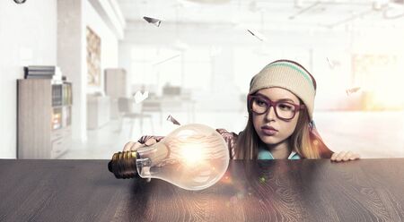 Attractive student girl in red glasses peeping from under tableの写真素材