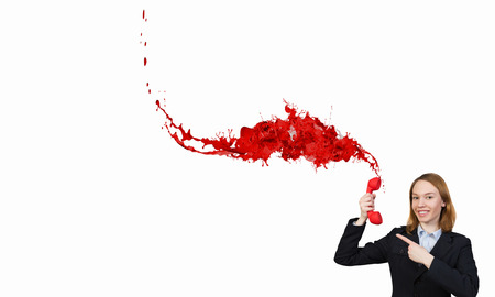 Young businesswoman with red phone receiver in handsの写真素材