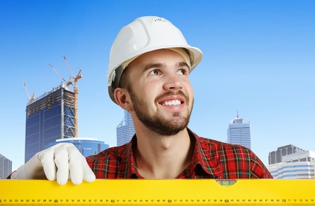 Builder man in checked shirt using measuring levelの写真素材