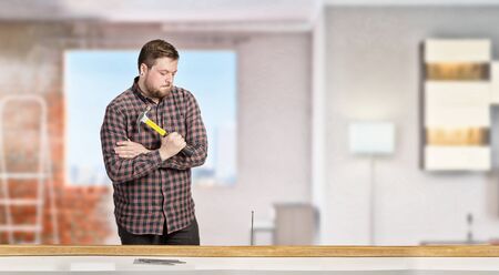 Casual man in checked shirt indoors with hammer and nails